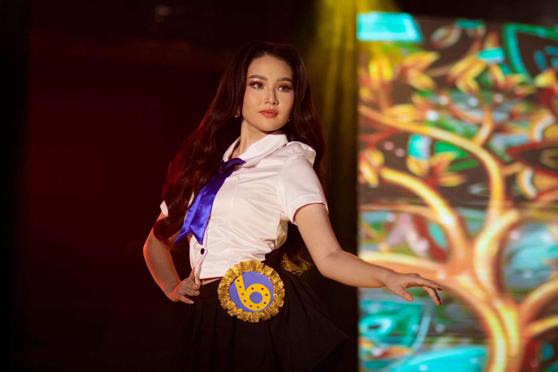 Uczennica w szkolnym mundurku występuje na kolorowej scenie w świetle reflektoró