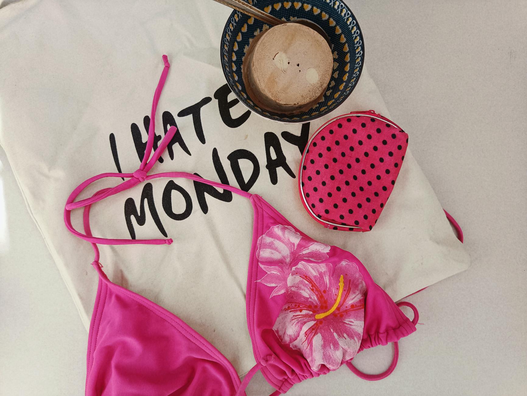 Różowy bikini, kokosowa miska i torba z napisem I Hate Monday na plaży