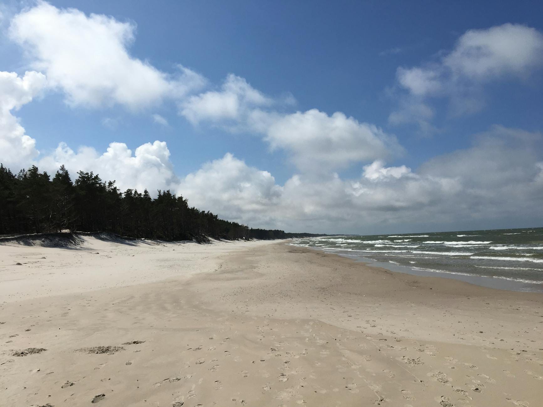 Spokojna plaża w Łebie nad Bałtykiem z delikatnymi falami i błękitnym niebem