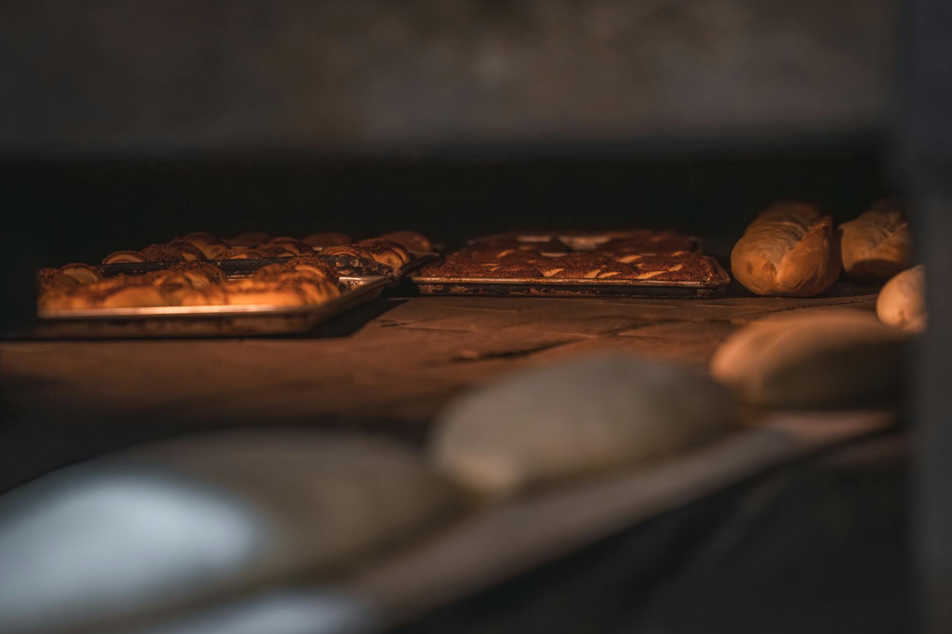 Bochny świeżo upieczonego chleba i bułek w piecu rzemieślniczej piekarni
