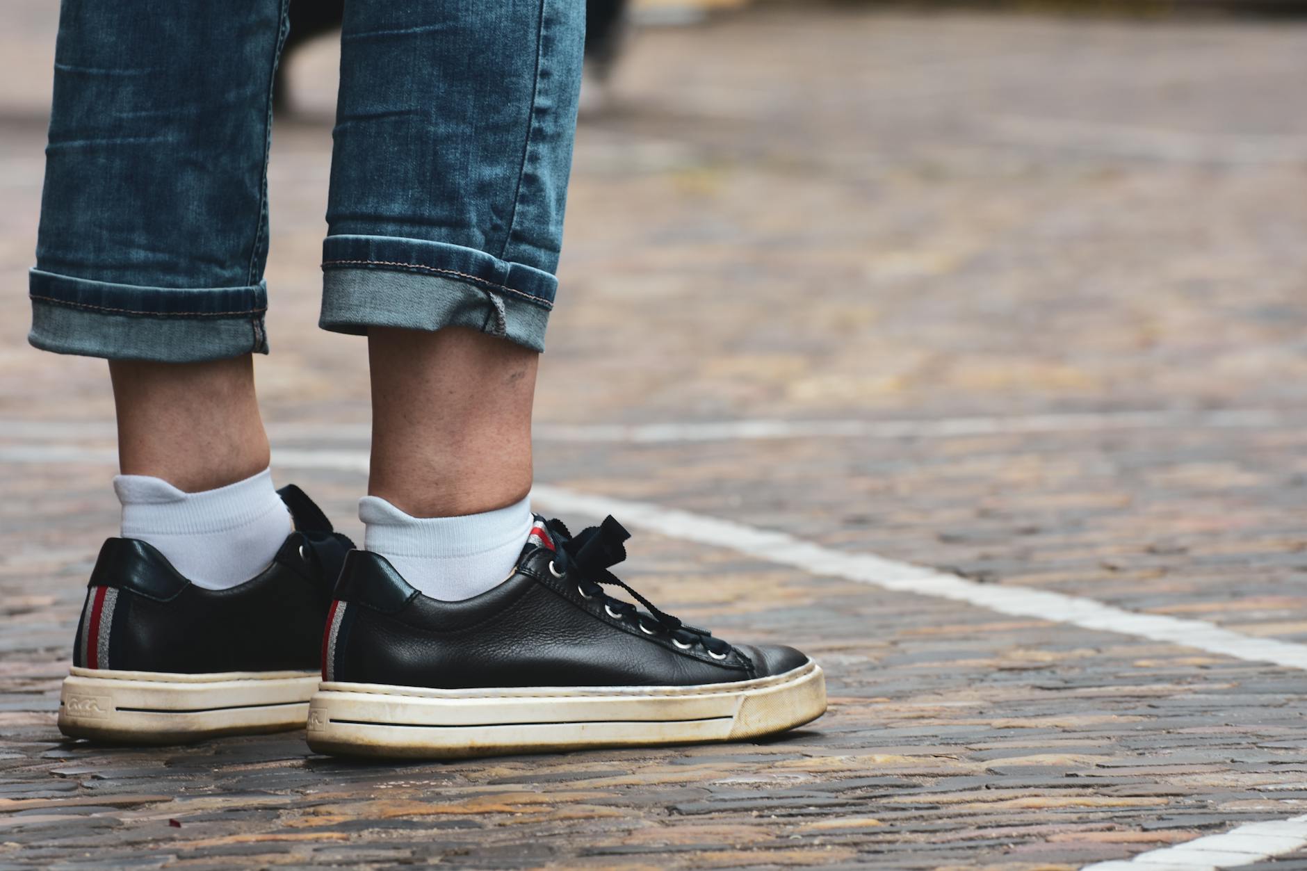 Czarne sneakersy i podwinięte dżinsy jako przykład codziennego stylu