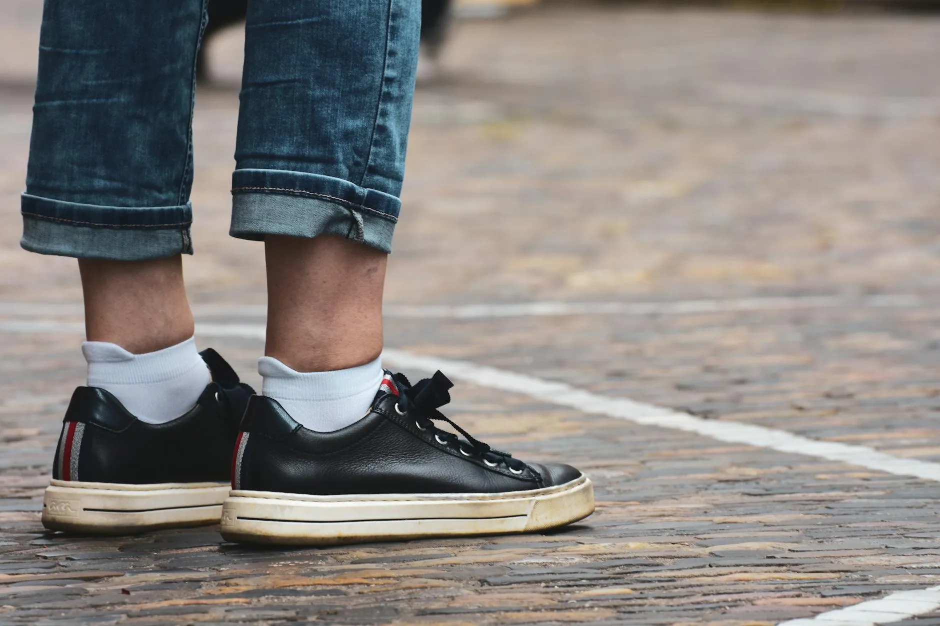Czarne sneakersy i podwinięte dżinsy jako przykład codziennego stylu