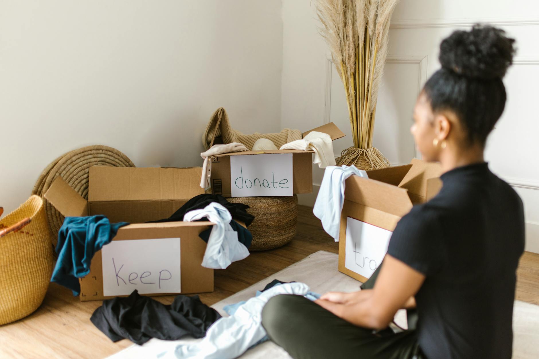 Decluttering dla zapracowanych: 5 minut dziennie, zero presji, realny efekt Kobieta segreguje ubrania do podpisanych pudeł z darami i rzeczami do zatrzymani