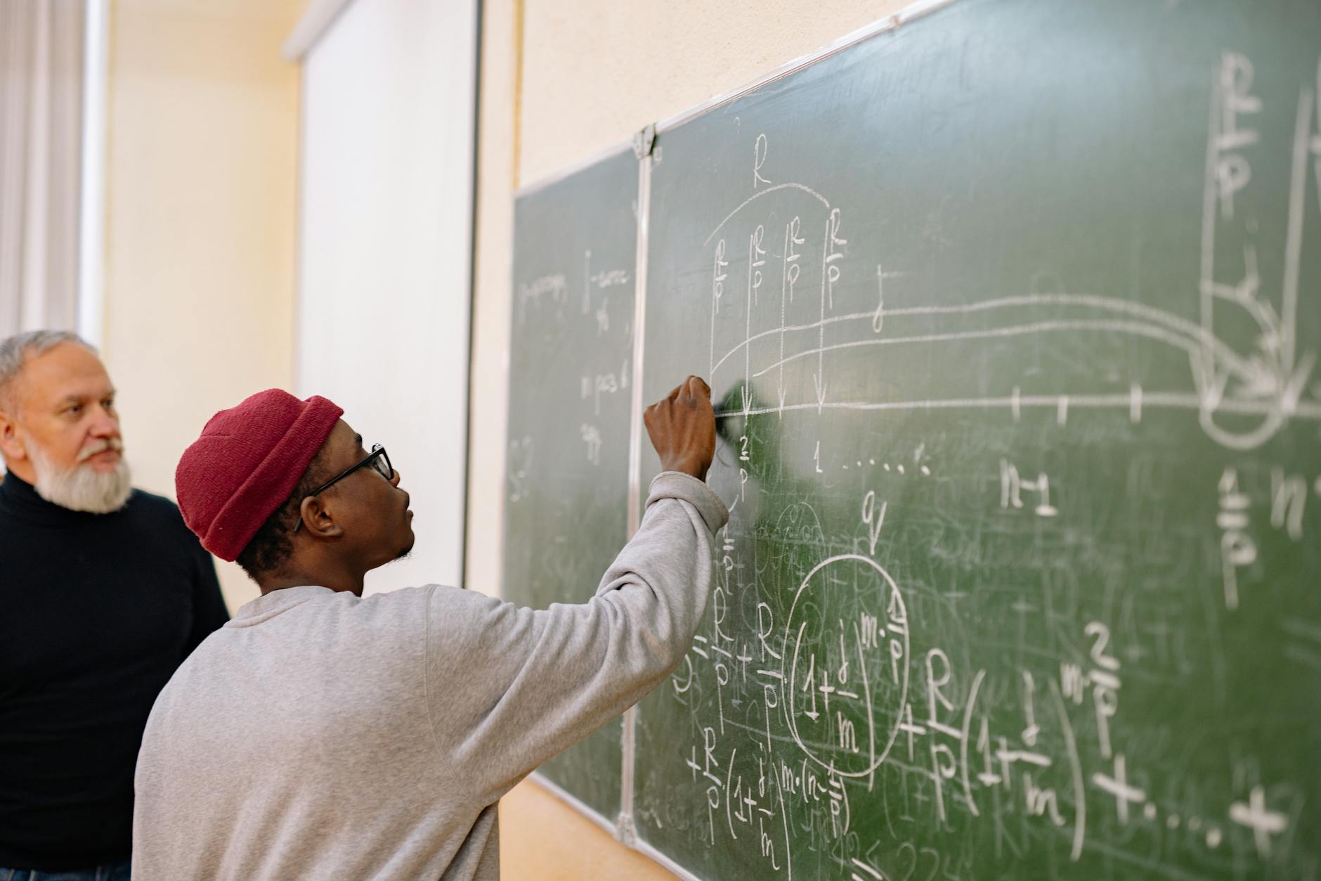 Student zapisuje złożone równania matematyczne na tablicy podczas wykładu