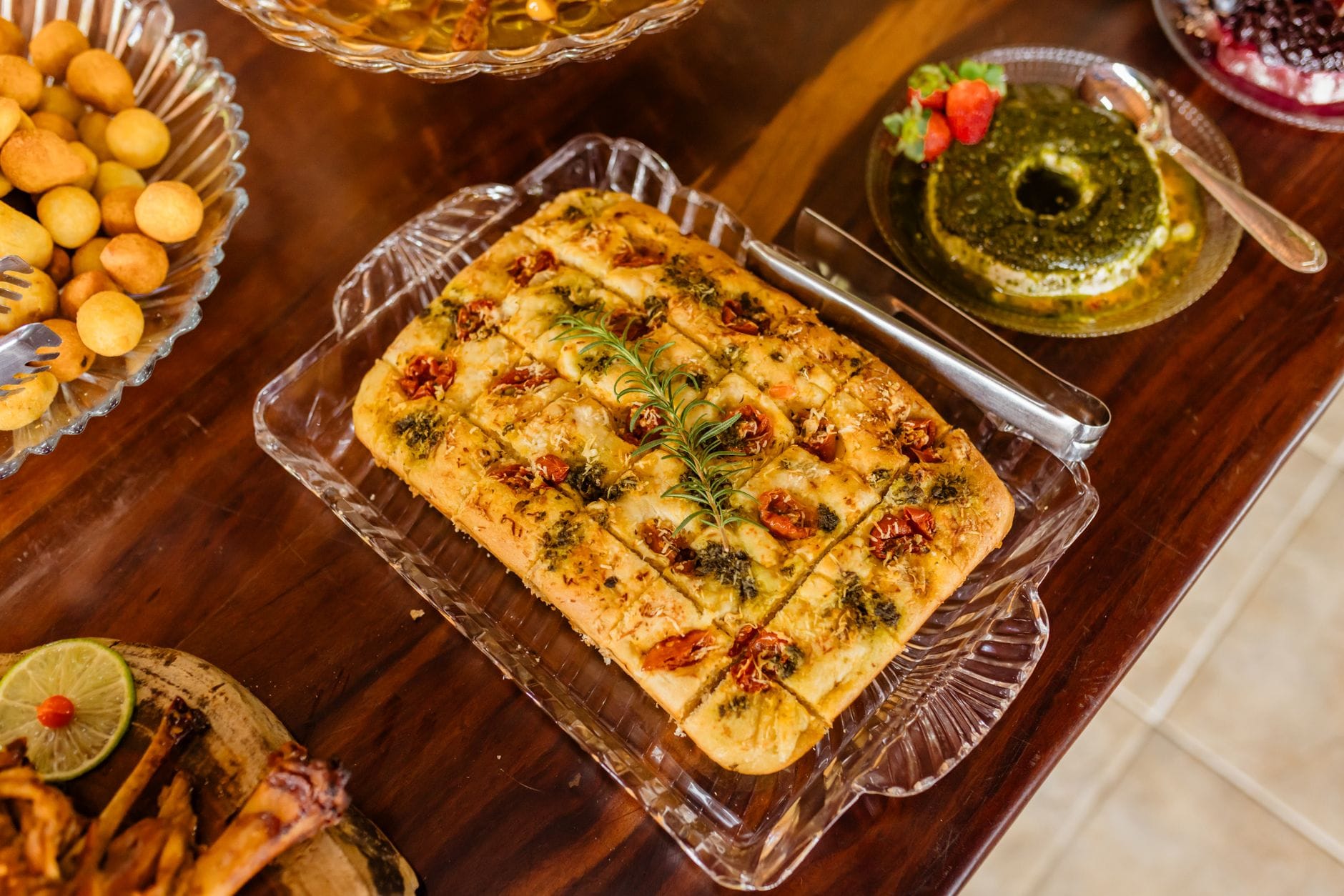 Focaccia z pomidorami podana z przystawkami na rustykalnym drewnianym stole