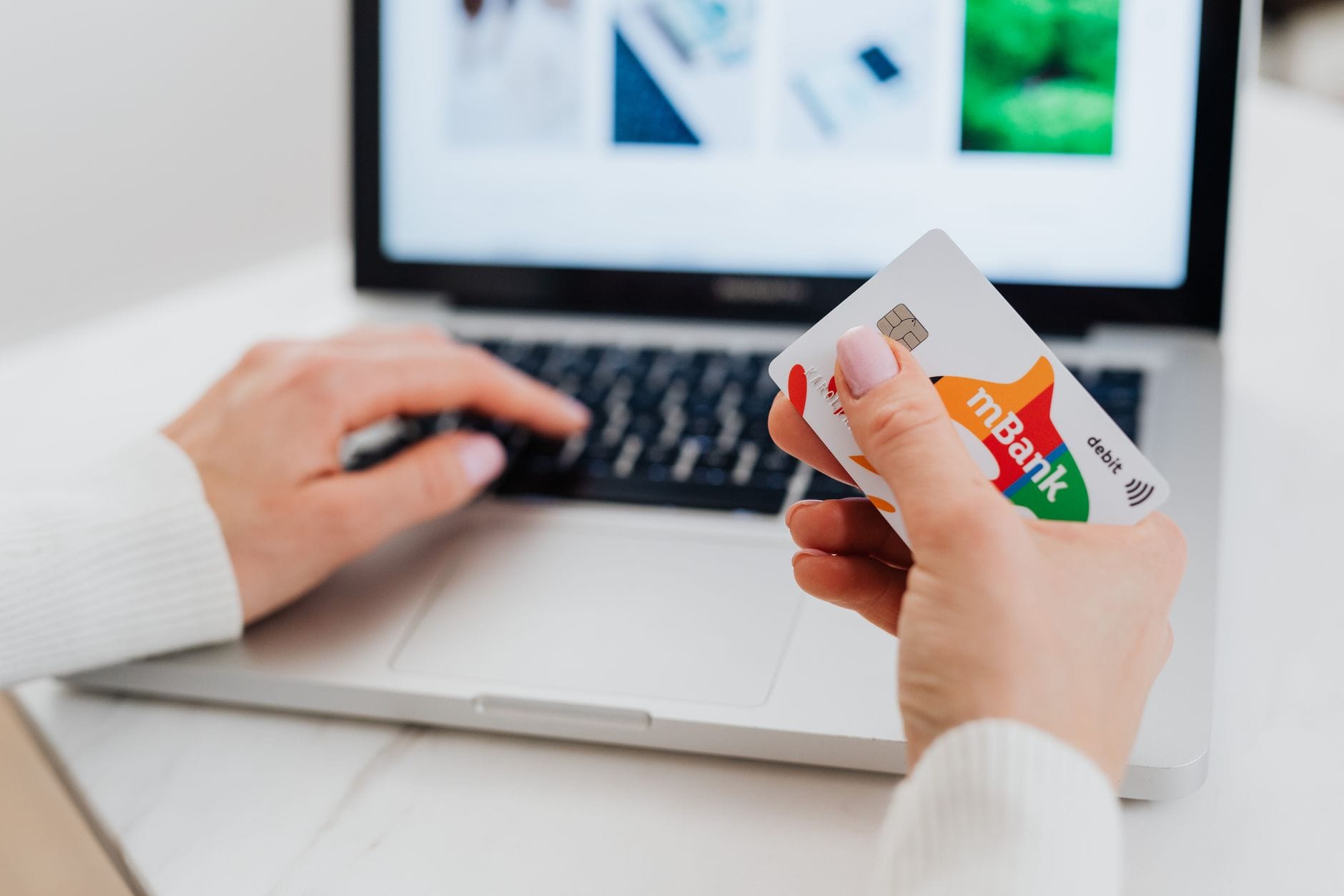 Ręce przy laptopie wpisujące dane karty podczas zakupów online