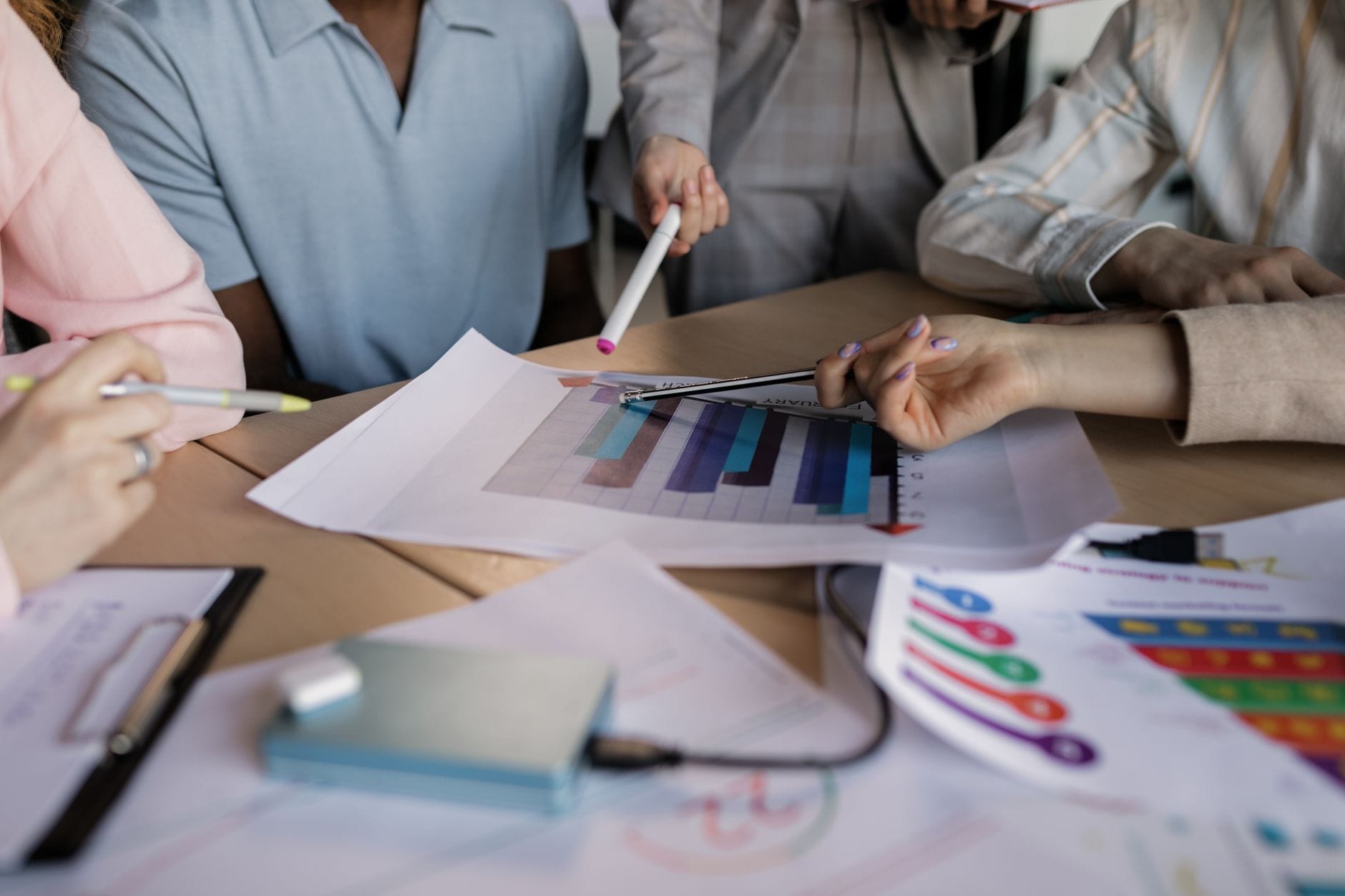 Zespół marketingowy małej firmy omawia strategię przy drewnianym stole Zespół marketingowy małej firmy omawia strategię przy drewnianym stole