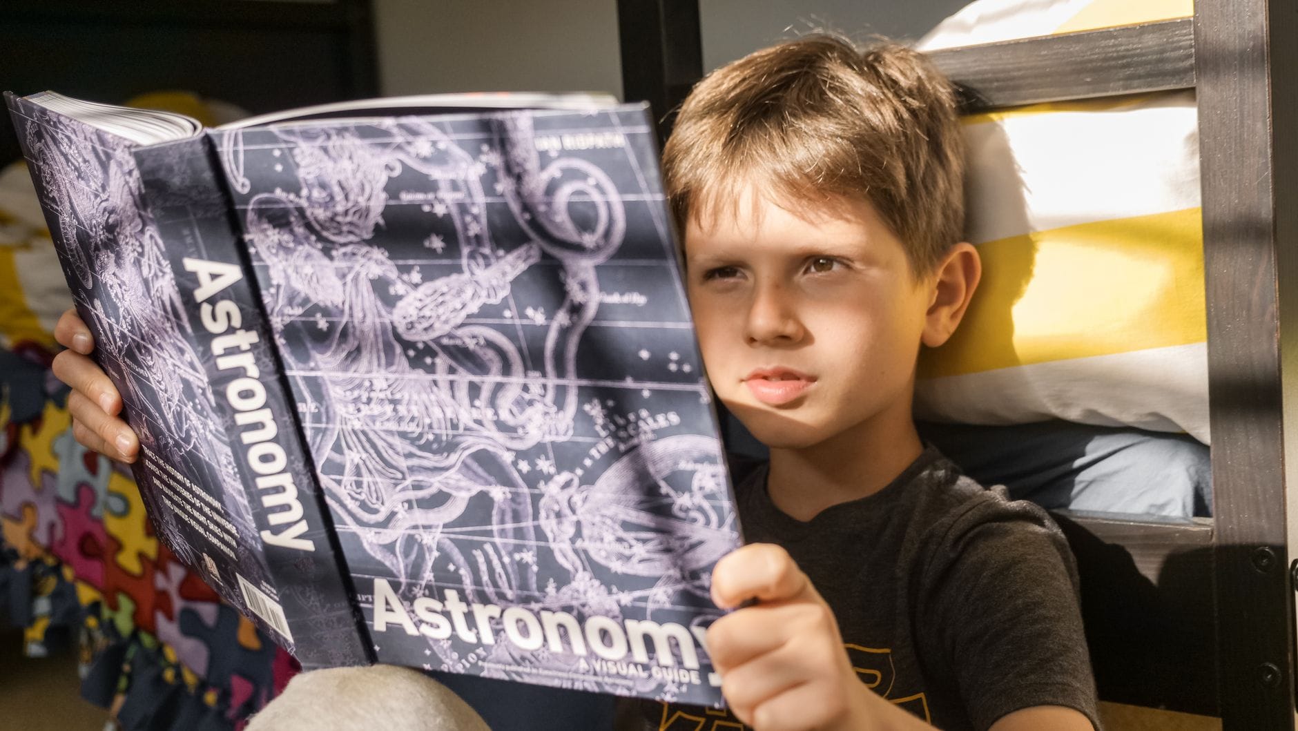 Chłopiec czyta książkę o astronomii przy świetle dziennym