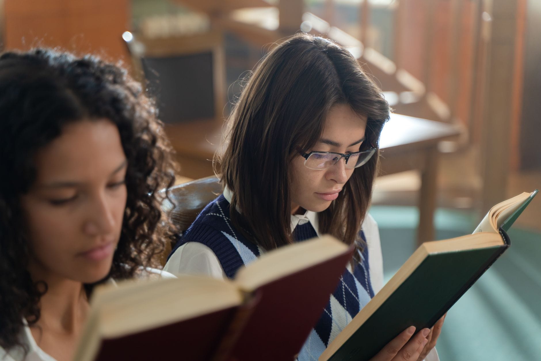 Dwie studentki czytają książki przy stoliku w sali edukacyjnej