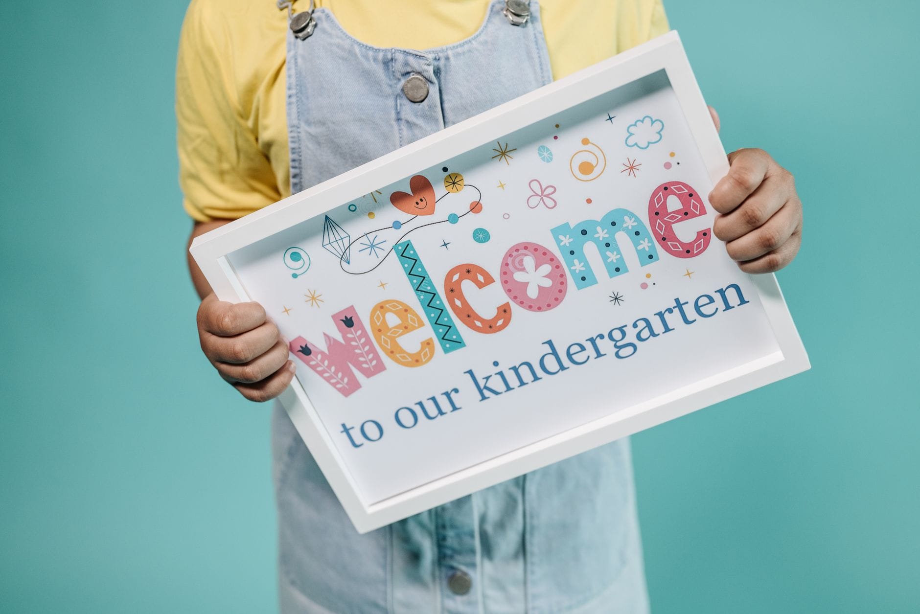 Dziecko trzyma kolorowy plakat z napisem welcome to kindergarten