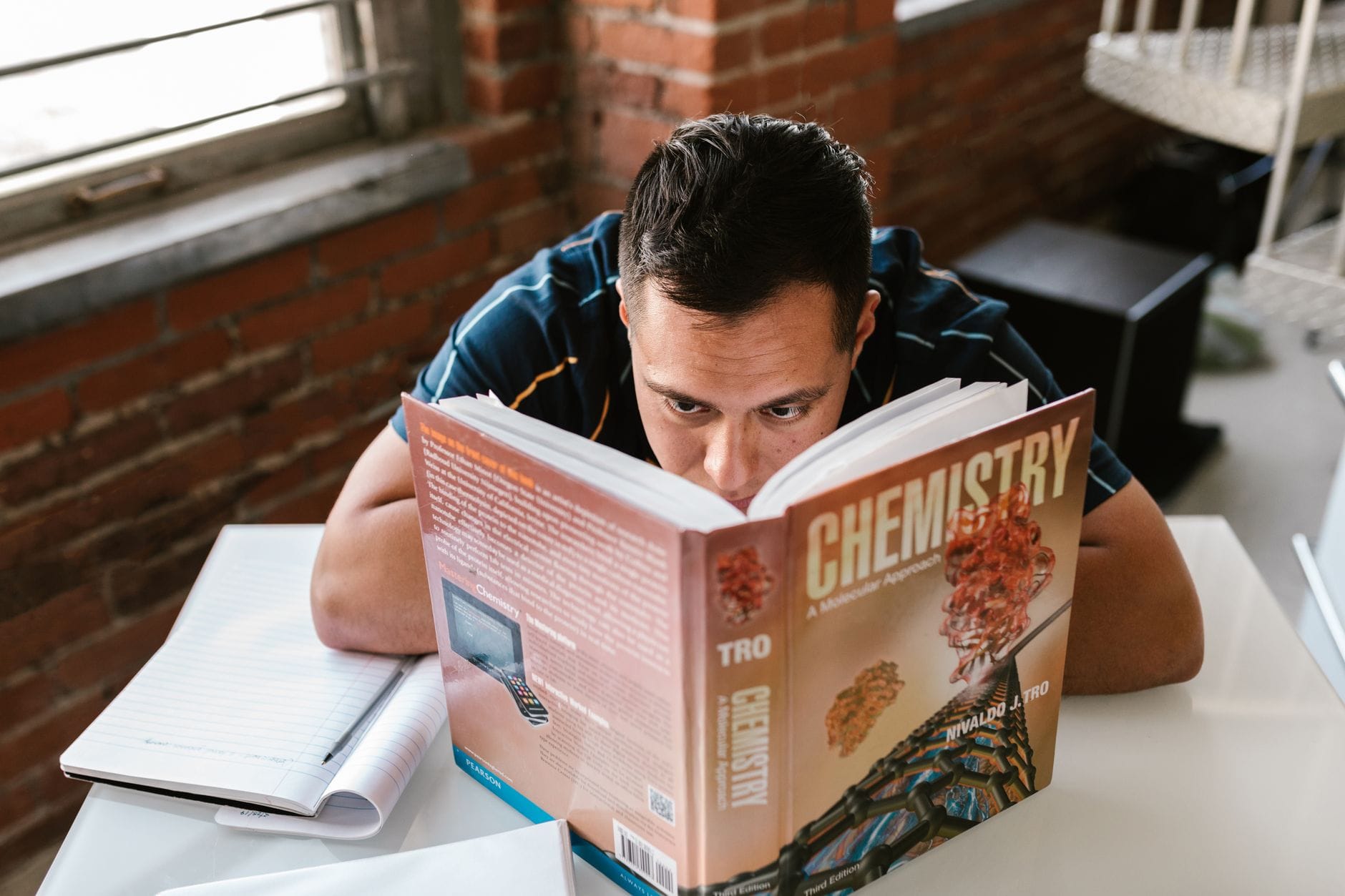 Mężczyzna przy biurku czyta podręcznik chemii w przytulnym gabinecie Mężczyzna przy biurku czyta podręcznik chemii w przytulnym gabinecie