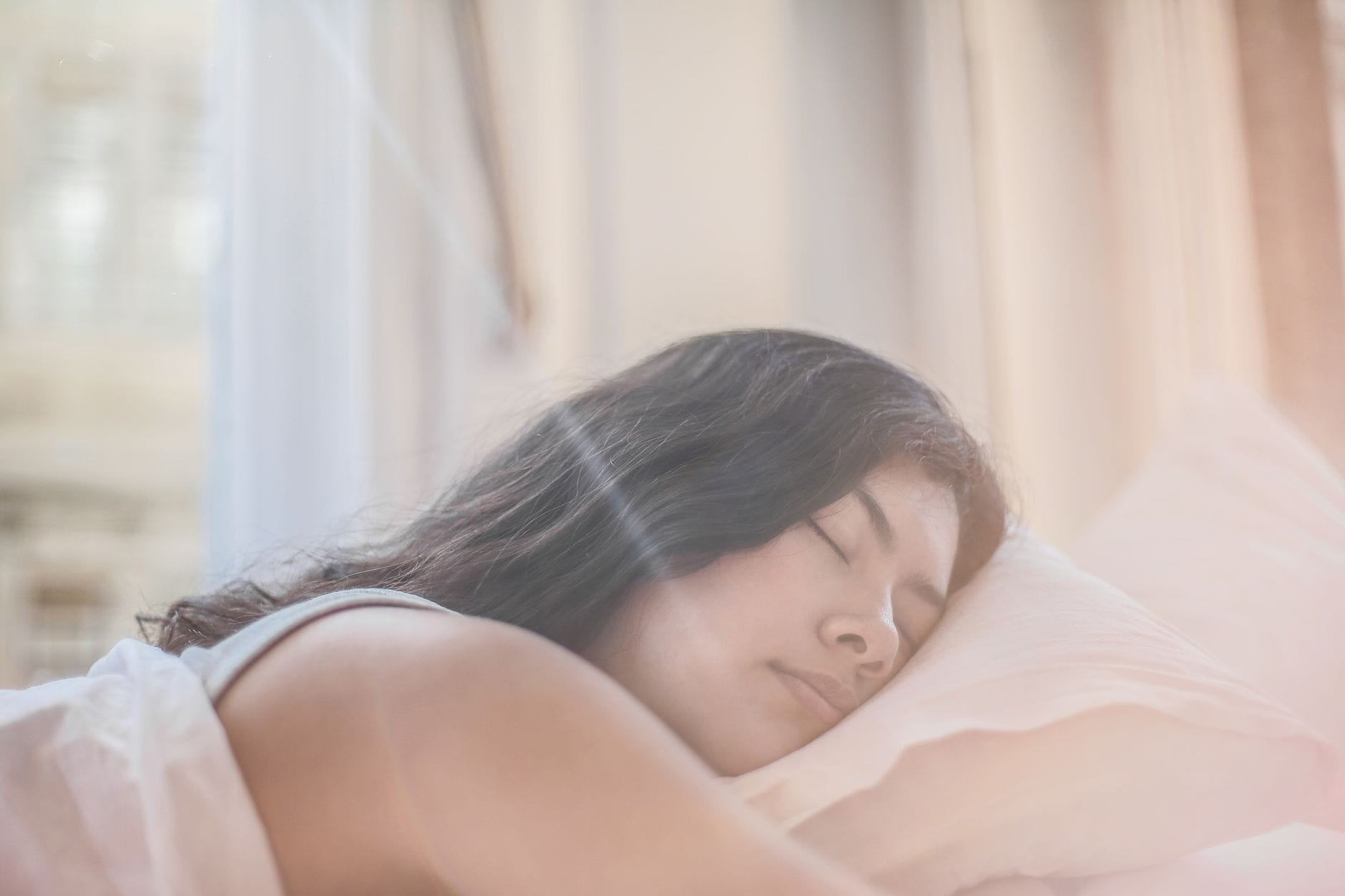Kobieta śpi spokojnie w miękkiej pościeli w porannym świetle